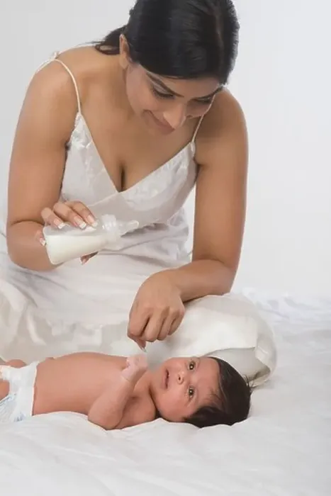 Framed Print : Woman checking milk before feeding her baby Framed Print : Woman checking milk before feeding her baby