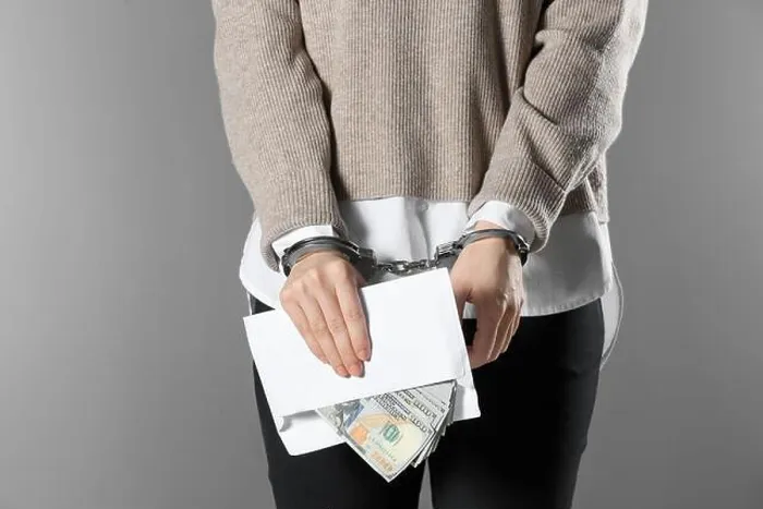 Framed Print : Woman in handcuffs holding bribe money on grey background, closeup Framed Print : Woman in handcuffs holding bribe money on grey background, closeup
