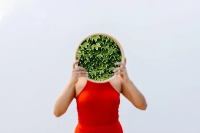 Framed Print : Woman holding mirror with reflection of plants in front of white wall Framed Print : Woman holding mirror with reflection of plants in front of white wall