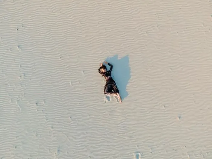 Framed Print : Woman in lace black dress lies in desert and casts a shadow on white sand. View from drone directly above Framed Print : Woman in lace black dress lies in desert and casts a shadow on white sand. View from drone directly above