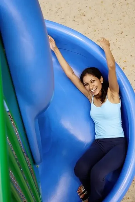 Framed Print : Woman sliding on slide, looking up at camera Framed Print : Woman sliding on slide, looking up at camera