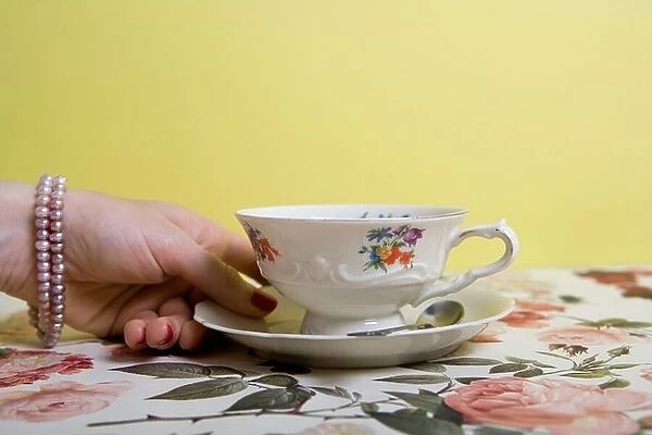 A woman's hand holding a cup and saucer