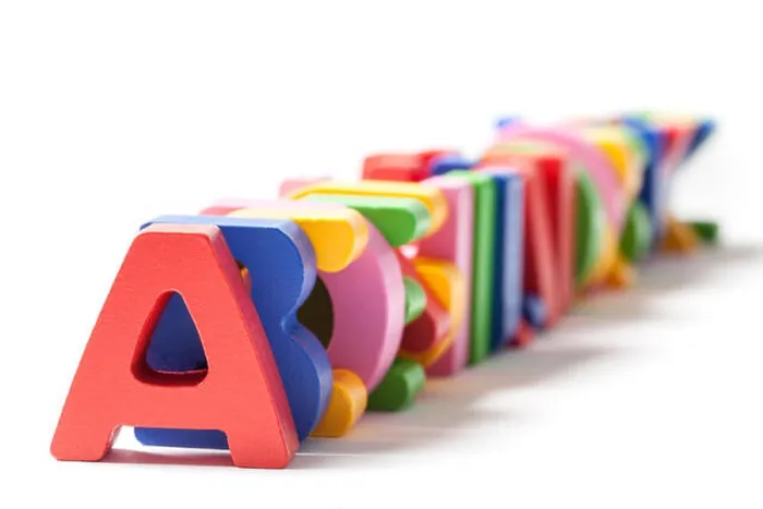 Framed Print : Wooden alphabet letters painted in different colors stacked one behind the other on white