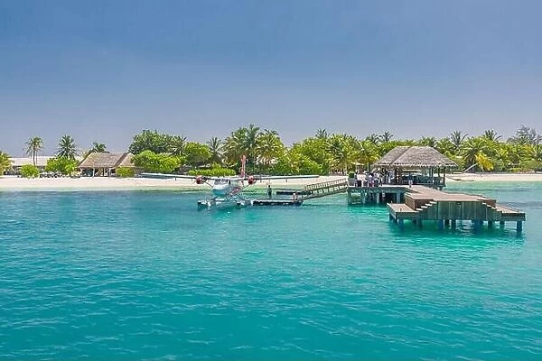 Wooden pier and jetty with seaplane at tropical island resort, Maldives. Luxury summer travel. Arrive at summer holiday vacation island landscape