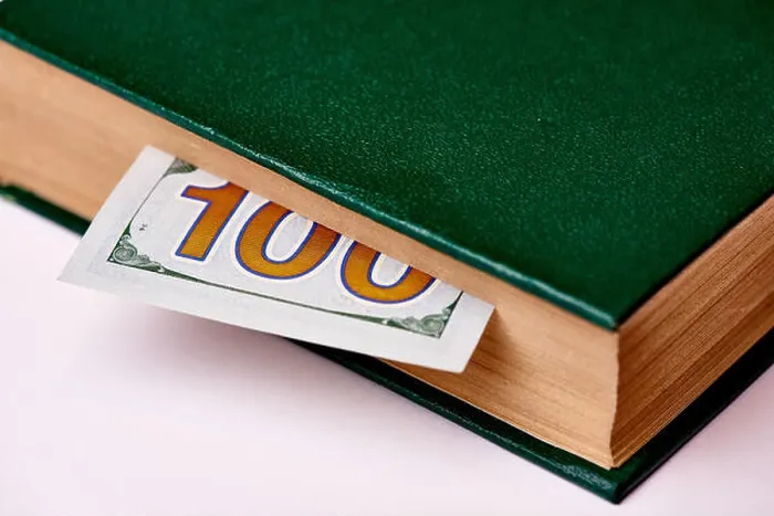 Framed Print : Bill worth one hundred US dollars in book on a white background macro Framed Print : Bill worth one hundred US dollars in book on a white background macro