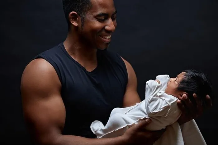 Framed Print : Young afro-american daddy holding his sweet newborn baby in the arms and looking at him with love. side view photo. first meeting with a adorable baby Framed Print : Young afro-american daddy holding his sweet newborn baby in the arms and looking at him with love. side view photo. first meeting with a adorable baby
