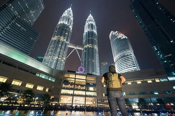 Young Asian man traveler wearing casual with backpack bag enjoy amazing weekends. Looking away to building in Kuala Lumpur, Malaysia. Asia