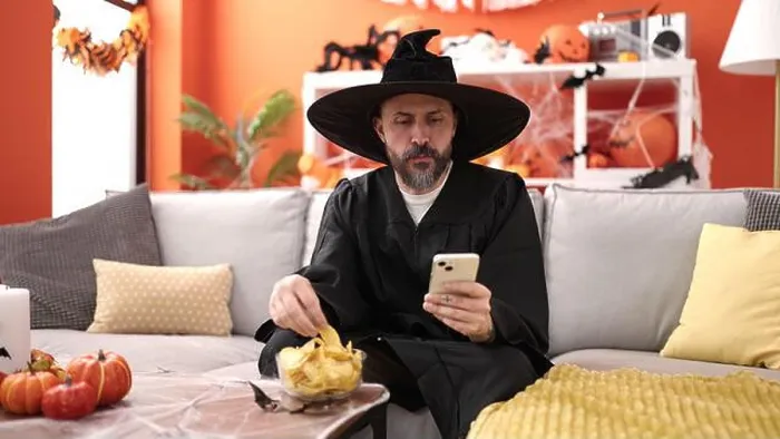 Framed Print : Young bald man wearing wizard costume eating chips potatoes using smartphone at home Framed Print : Young bald man wearing wizard costume eating chips potatoes using smartphone at home