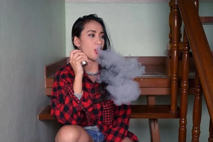 Framed Print : Young beautiful Asian woman vaping at home Framed Print : Young beautiful Asian woman vaping at home