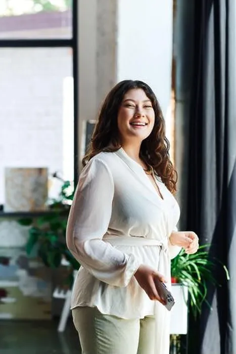 Framed Print : A young beautiful plus size woman stands happily in her stylish office, surrounded by plants Framed Print : A young beautiful plus size woman stands happily in her stylish office, surrounded by plants