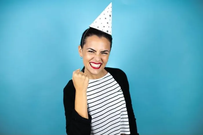 Framed Print : Young beautiful woman wearing a birthday hat over insolated blue background angry and mad raising fist frustrated Framed Print : Young beautiful woman wearing a birthday hat over insolated blue background angry and mad raising fist frustrated