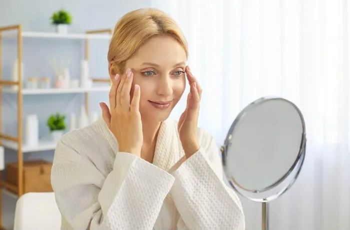 Framed Print : Young blonde woman in bathrobe gently touching her face skin