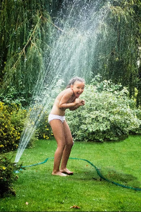 Framed Print : Young girl having fun while standing under garden fountain during hot summer day Framed Print : Young girl having fun while standing under garden fountain during hot summer day