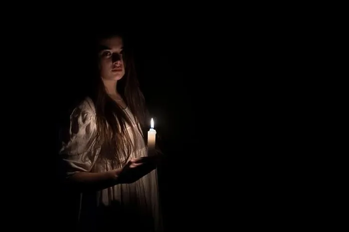 Framed Print : A young girl in an old white dress holding a candle in her hand and staring at the camera. Copy space on the right side. Dark background Framed Print : A young girl in an old white dress holding a candle in her hand and staring at the camera. Copy space on the right side. Dark background