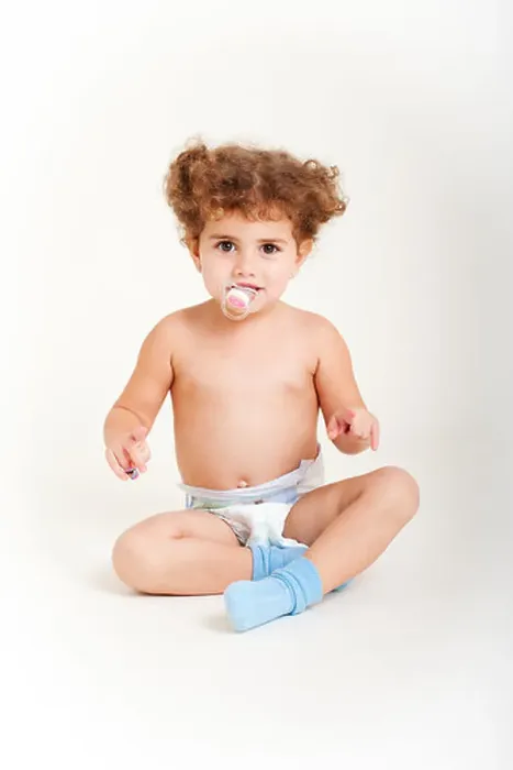 Framed Print : Young girl with pacifier, age 2, sits down on white canvas wearing diaper, blue socks Framed Print : Young girl with pacifier, age 2, sits down on white canvas wearing diaper, blue socks