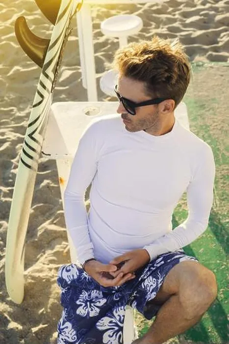 Framed Print : Young handsome smiling man is sitting on a beach next to his surfboard wearing dark sunglasses Framed Print : Young handsome smiling man is sitting on a beach next to his surfboard wearing dark sunglasses