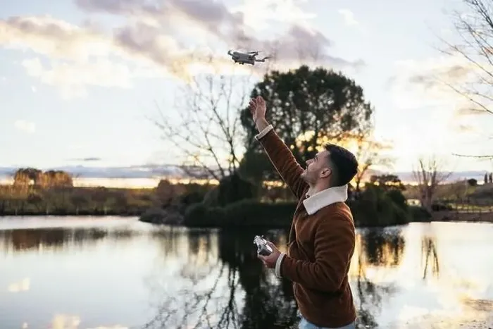 Framed Print : Young man using a drone near a lake to record and photograph the landscape Framed Print : Young man using a drone near a lake to record and photograph the landscape