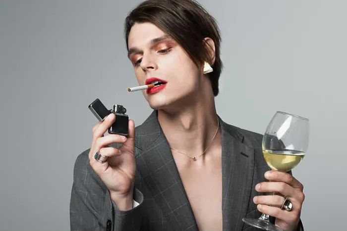 Framed Print : young transgender man in blazer holding glass of wine and lighter while smoking isolated on grey Framed Print : young transgender man in blazer holding glass of wine and lighter while smoking isolated on grey