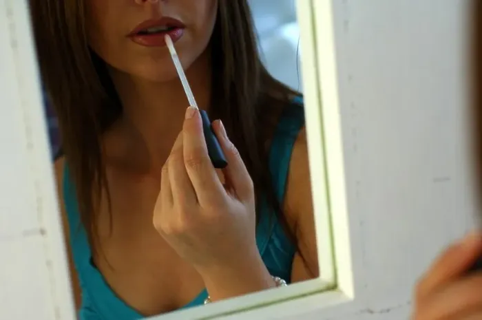 Framed Print : Young woman applying make up in a mirror Framed Print : Young woman applying make up in a mirror