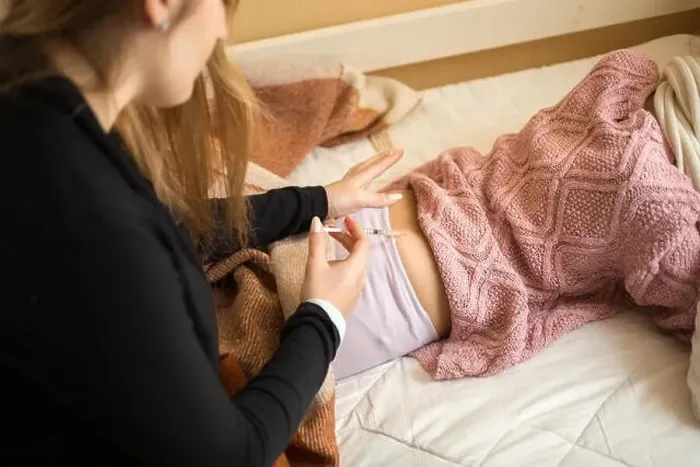 Framed Print : Young woman doing injection in girls bottom lying on bed Framed Print : Young woman doing injection in girls bottom lying on bed