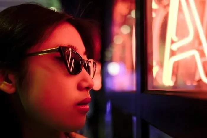 Framed Print : Young woman wearing sunglasses by illuminated wall with neon lights