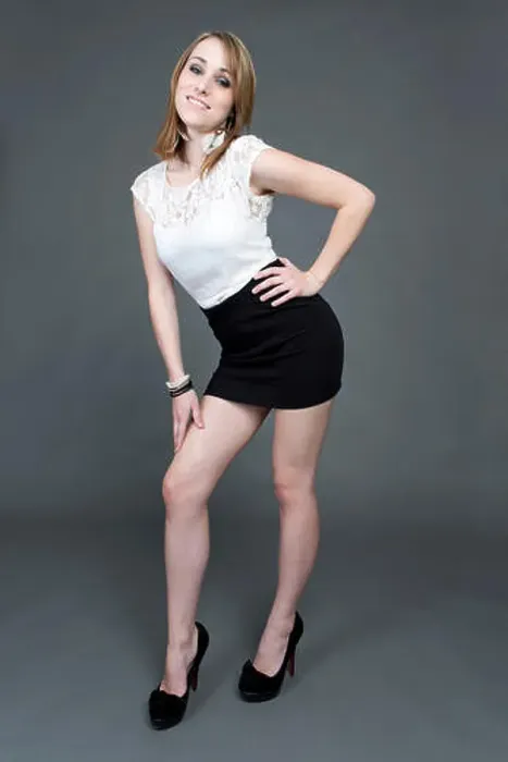 Framed Print : Young woman wearing a white top, a short black skirt and high heels