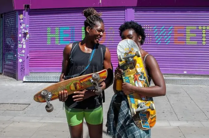 Framed Print : Two young women holding skateboards on a hot summers day in London's Camden Town Framed Print : Two young women holding skateboards on a hot summers day in London's Camden Town