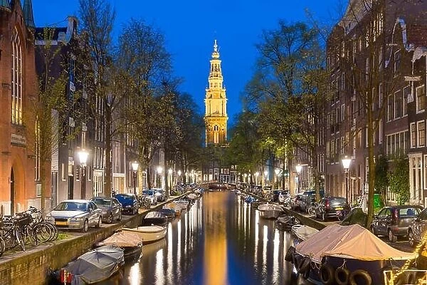 Zuiderkerk church tower at the end of a canal in the city of Amsterdam, The Netherlands at night