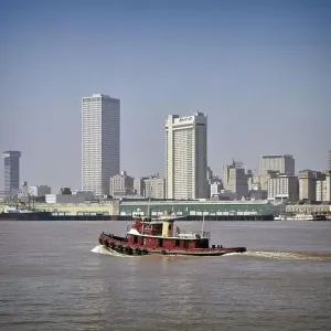 1970s CENTER CITY SKYLINE WITH TUG BOAT ON MISSISSIPPI RIVER IN FOREGROUND NEW ORLEANS LOUISIANA USA - kr28018 GRD001 HARS EDIFICE MUDDY WATERFRONT