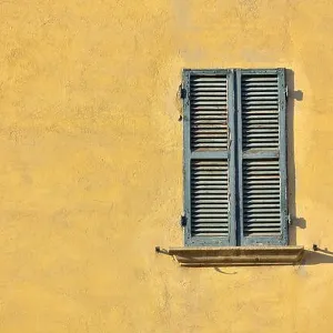 Closed green windows on yellow wall of old house in Florence city, Italy