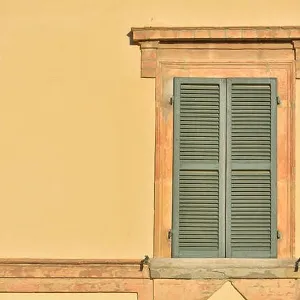 Closed green windows on yellow wall of old house in Florence city, Italy