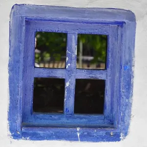 Closed vintage blue window on white wall of old house in romania