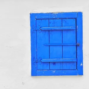 Closed vintage blue window on white wall of old house in romania