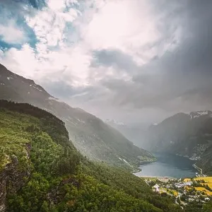 Geirangerfjord, Norway - Geiranger In Geirangerfjorden In Rainy Summer Day. Famous Norwegian Landmark And Popular Destination Geirangerfjord, Norway - Geiranger In Geirangerfjorden In Rainy Summer Day. Famous Norwegian Landmark And Popular Destination
