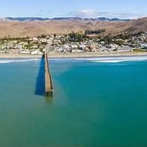 A long pier reaches out into the Pacific Coast in the quaint city of Cayucos, California. This central California region is known for its scenic A long pier reaches out into the Pacific Coast in the quaint city of Cayucos, California. This central California region is known for its scenic