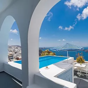 Luxury Greek holidays in Santorini. White architecture, chairs over sea view and umbrella with empty infinity pool Santorini. Summer vacation, holiday