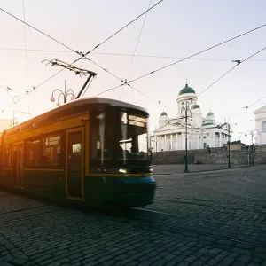 Tram passing Helsinki Senate Square during sunset with Helsinki Cathedral in the background at Finland