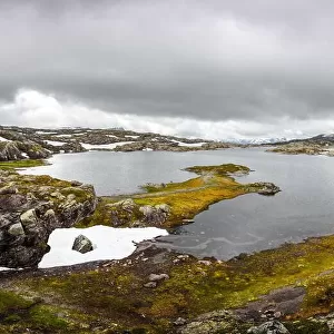 Typical norwegian landscape with snowy mountains and clear lake near the Trolltunga rock - most spectacular and famous scenic cliff in Norway