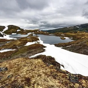 Typical norwegian landscape with snowy mountains and clear lake near the famous Aurlandsvegen (Bjorgavegen), mountain road, Aurland, Norway