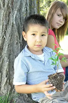Pre Adolescent Prints: 13 year old girl and six year old boy with small tree seated beside tree, Winnipeg, Canada