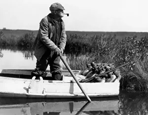 Grown Up Prints: 1920s 1930s SENIOR MAN DUCK HUNTER STANDING IN SNEAK-BOX BOAT ABOUT TO DEPLOY DECOYS IN BARNEGAT BAY WETLANDS MARSH NEW