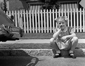 Old Fashioned Prints: 1940s GIRL SITTING ON CURB WITH TOOTH TIED TO BACK OF CAR FENDER LOOKING AT CAMERA