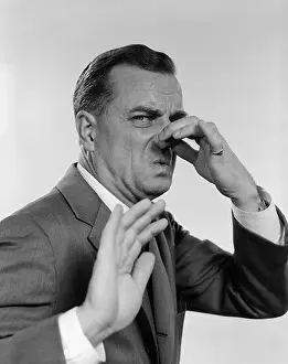 Smelling Prints: 1950s 1960s MAN 3/4 PROFILE HAND HOLDING NOSE CLOSED HAND OUT TOWARD CAMERA FACIAL EXPRESSION DISGUST STINKING