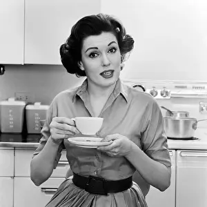Hars Prints: 1950s 1960s PORTRAIT WOMAN HOUSEWIFE IN KITCHEN DRINKING CUP OF COFFEE SPEAKING LOOKING AT CAMERA