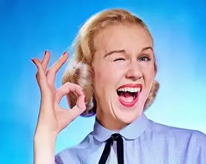Old Fashion Prints: 1950s ENTHUSIASTIC BLOND WOMAN MOUTH OPEN WINKING EYE LOOKING AT CAMERA AND MAKING OK SIGN WITH THUMB AND FINGER