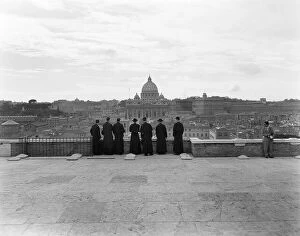 Wish You Were Here Collection: 1950s ROME ITALY BACK VIEW OF STUDENT PRIESTS LINED UP BY WALL OVERLOOKING CITY WITH VIEW OF ST