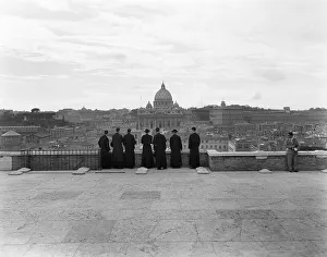 Occupations Prints: 1950s ROME ITALY BACK VIEW OF STUDENT PRIESTS LINED UP BY WALL OVERLOOKING CITY WITH VIEW OF ST