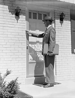 Occupations Prints: 1950s SALESMAN WEARING SUIT TIE HAT CARRYING BRIEFCASE RINGING SUBURBAN HOUSE DOORBELL