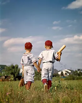 Old Fashion Prints: 1960s TWO BOYS BROTHERS WEARING LITTLE LEAGUE BASEBALL UNIFORMS HOLDING HANDS WALKING AWAY FROM CAMERA - kj3545 HAR001