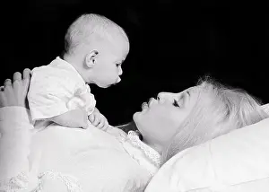 Mothers Prints: 1970s BLONDE WOMAN MOTHER LYING DOWN WITH BABY DAUGHTER ON HER CHEST LOOKING EYE-TO-EYE BABY IMITATING MOTHER'S